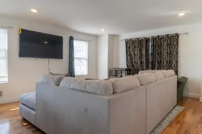a living room with a large couch and a flat screen tv at Spacious 3BR Home Near Newark Airport in Newark