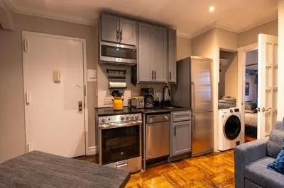 a kitchen with stainless steel appliances and a living room at Prestige Gramercy Park Suites in New York