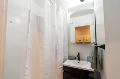 a bathroom with a white shower curtain and a sink at Prestige Gramercy Park Suites in New York