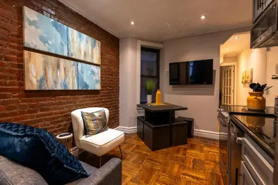 a living room with a couch and a tv and a brick wall at Prestige Gramercy Park Suites in New York