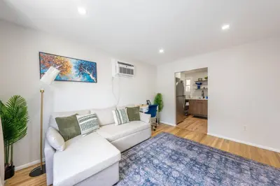 a living room with a white couch and a blue rug at Modern 2BR 8 mins to Penn Station with WiFi and Laundry in Newark