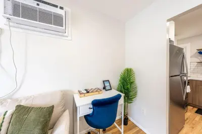 a white living room with a blue chair and a desk at Modern 2BR 8 mins to Penn Station with WiFi and Laundry in Newark