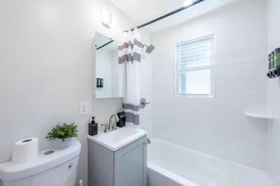 a white bathroom with a sink and a toilet at Modern 2BR 8 mins to Penn Station with WiFi and Laundry in Newark
