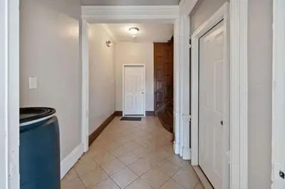 a hallway with a white door and a tile floor at Modern 2BR Near NYC with Free Parking and Workspace in East Orange