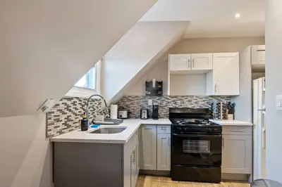 a small kitchen with white cabinets and a sink at Modern 2BR Near NYC with Free Parking and Workspace in East Orange