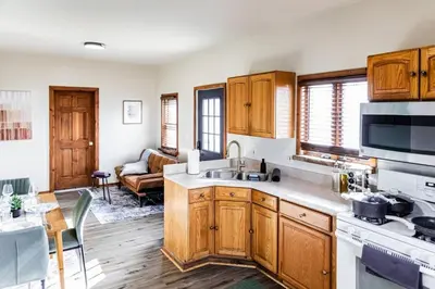 a kitchen with wooden cabinets and a living room at Charming 2 Bedroom Apartment Near NYC, Metlife Stadium in Hackensack