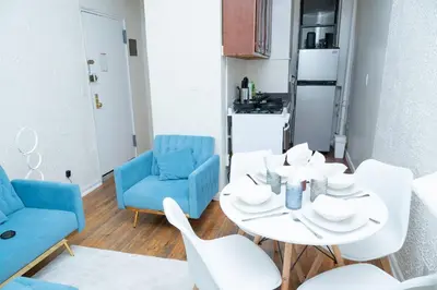 a living room with a white table and blue chairs at Elegant84 West Side Home 5 min to Central Park in New York