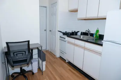 a white kitchen with a desk and a chair in it at Chic12 East Village Apartment Near Union Square Top Dining n Shopping in New York