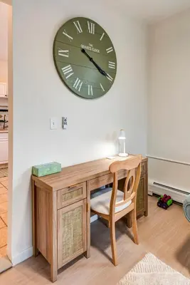 a clock on a wall above a desk with a chair at Serene Hamilton ELM 13MI to Time Square Laundry Easy Parking in Teaneck