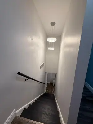 a hallway with a staircase with a light fixture at Spacious private room in a new house with private bathroom close to center city in Philadelphia