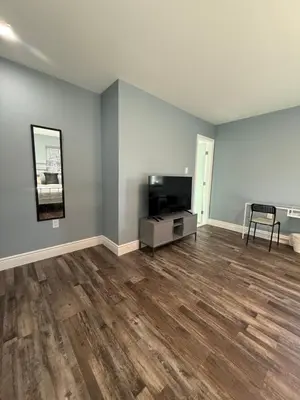an empty living room with a television and wooden floors at Spacious private room in a new house with private bathroom close to center city in Philadelphia