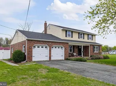 a brick house with two white garage doors at The Carneys Point Cottage