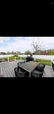 a wooden deck with a picnic table and chairs at The Carneys Point Cottage