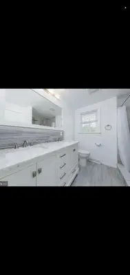 a white bathroom with a sink and a toilet at The Carneys Point Cottage
