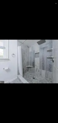 a white bathroom with a shower and a sink at The Carneys Point Cottage