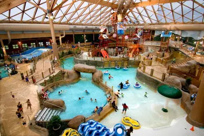an indoor pool with people in a water park at Moonlight Mountain Lodge on Camelback Mountain! in Tannersville