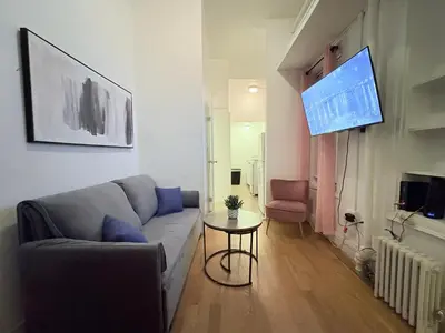 a living room with a couch and a table and a tv at Hudson Crown Suites in New York