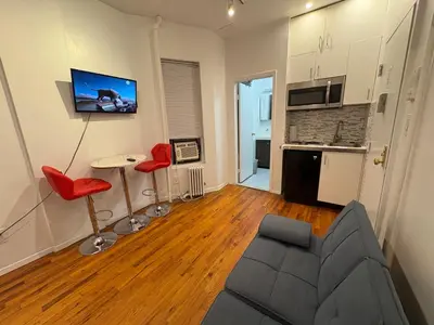 a living room with a couch and two red chairs at Hudson Crown Suites in New York