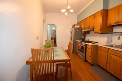 a kitchen with wooden cabinets and a table and a refrigerator at Cerca de Nueva York, Confortable in West New York