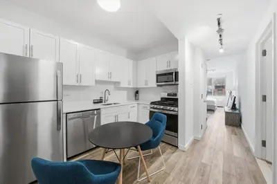 a kitchen with white cabinets and a table and blue chairs at The Aurora in New York