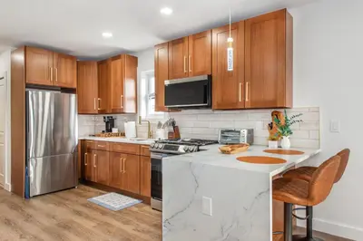 a kitchen with wooden cabinets and a stainless steel refrigerator at Apartment in Irvington Unit B in Irvington