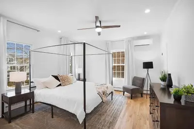 a white bedroom with a bed and a chair at Montclair's Best Stays in Montclair