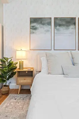 a bedroom with a white bed and a table with a lamp at Casa Kanso in Jersey City