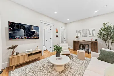 a living room with a couch and a tv on a wall at Casa Kanso in Jersey City
