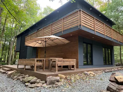 a small house with a table and an umbrella at Pine Breeze in Pocono Pines