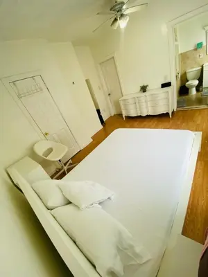 a white bed in a room with a ceiling fan at Spacious Private Room with Private Bath in Paterson