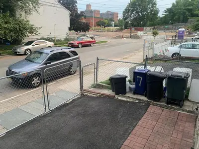 a car parked next to a fence with trash cans at Spacious Private Room with Private Bath in Paterson