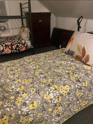 a bed with a blanket with yellow flowers on it at Vibrant home all to yourself in Newark