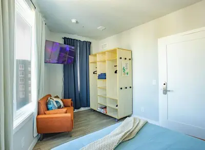 a room with a bed and a chair and a cabinet at Sky-view 2BD Apartment In Northern Liberties in Philadelphia