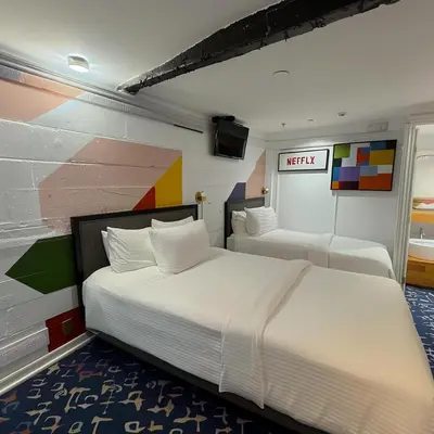 two beds in a room with a wall with a mural at The Helton Suites at Midtown in New York