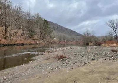 a river with rocks and trees and a mountain at Delaware River Retreat