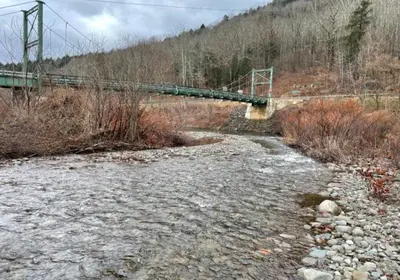 a bridge over a river with rocks and a bridge at Delaware River Retreat