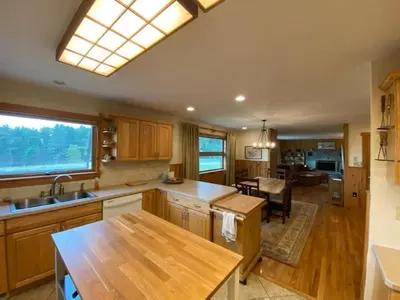 a kitchen with wooden cabinets and a dining room at Apple Orchard & Forest Retreat with Woodland Pond in Forestburgh
