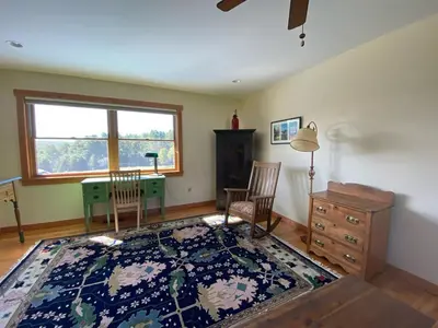 a living room with a desk and chairs and a rug at Apple Orchard & Forest Retreat with Woodland Pond in Forestburgh