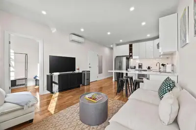 a living room with a white couch and a kitchen at Carroll Place II - Bright 3BR Carroll Gardens Apt in Brooklyn