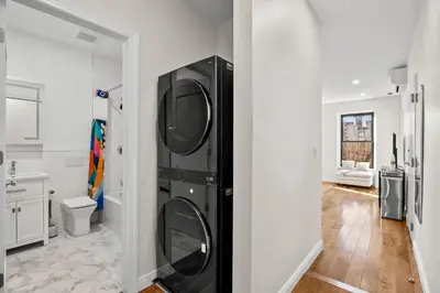 a black washer and dryer in a white bathroom at Carroll Place II - Bright 3BR Carroll Gardens Apt in Brooklyn