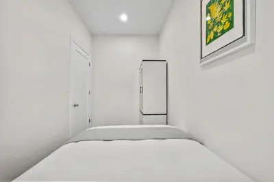 a white bedroom with a bed and a mirror at Carroll Place II - Bright 3BR Carroll Gardens Apt in Brooklyn