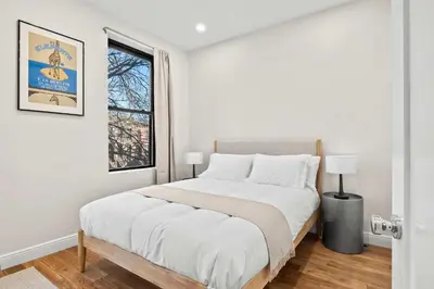 a white bedroom with a large bed and a window at Carroll Place II - Bright 3BR Carroll Gardens Apt in Brooklyn