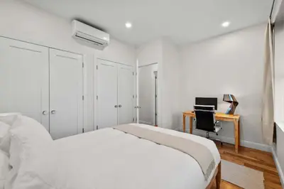 a white bedroom with a bed and a desk at Carroll Place II - Bright 3BR Carroll Gardens Apt in Brooklyn