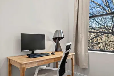 a desk with a computer on it next to a window at Carroll Place II - Bright 3BR Carroll Gardens Apt in Brooklyn