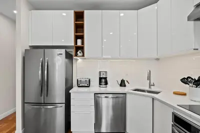 a kitchen with white cabinets and a stainless steel refrigerator at Carroll Place II - Bright 3BR Carroll Gardens Apt in Brooklyn
