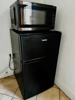 a microwave sitting on top of a black refrigerator at Private Studio Near NYC - Easy Commute & Workspace in Guttenberg