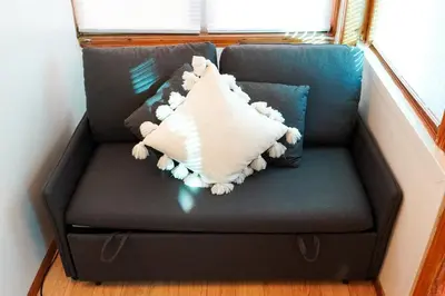 a couch with a pillow on it in a room at Private Studio Near NYC - Easy Commute & Workspace in Guttenberg