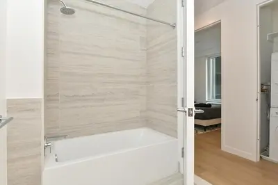 a bathtub in a bathroom with a glass door at Contemporary Luxury 3BR 2BA Downtown NYC in New York