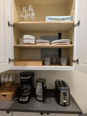a cupboard with plates and cups and a coffee maker at The Midtown Sanctuary - Private Silent Suite at Times Square in New York