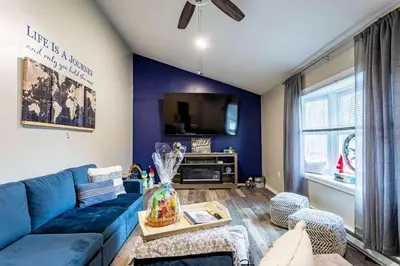 a living room with a blue couch and a tv at Summit Retreat Hot Tub Game Room Sauna in Tobyhanna